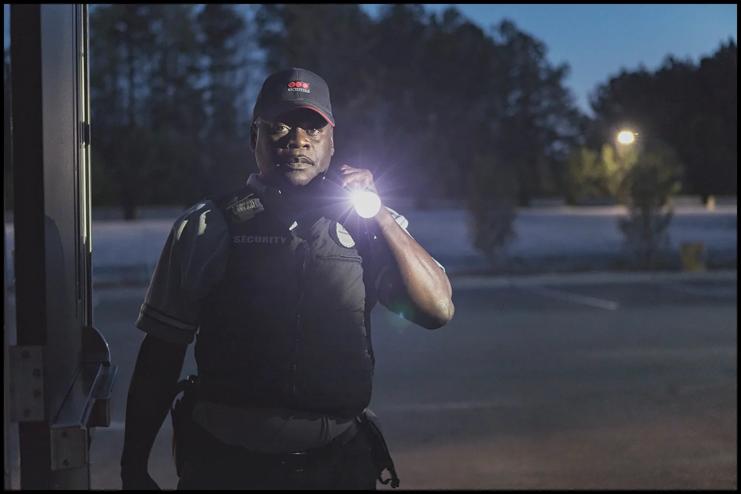 Corporate photography by Michael LoBiondo of male security guard with flashlight at night on locatio Corporate photography of male security guard with flashlight at night on location