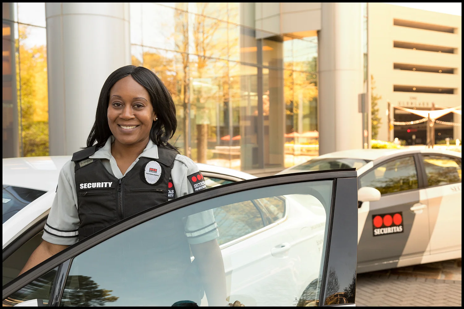 Corporate photography by Michael LoBiondo of smiling female security officer outside by car on location Corporate photography of smiling female security officer outside by car on location
