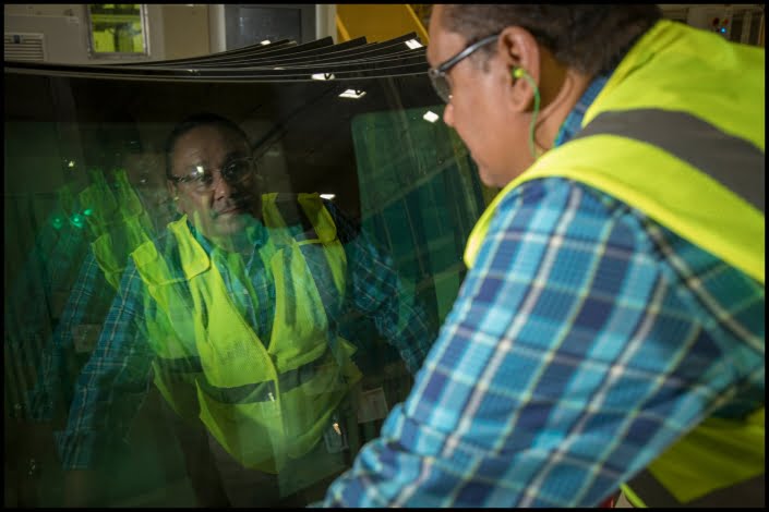 Worker examining windshield at quality control