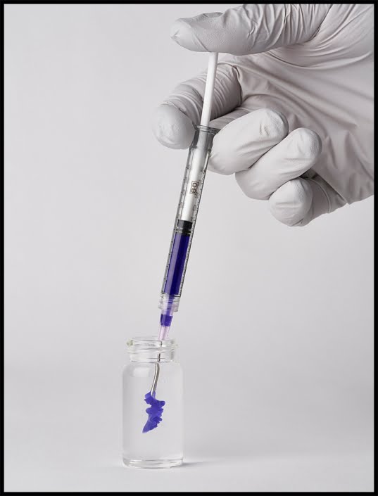Injecting purple plastic material into glass vial
