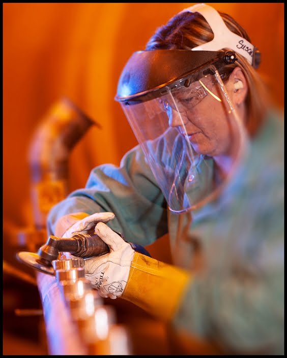 Manufacturing worker grinding metal pipe