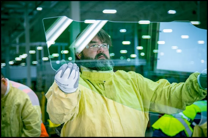 glass-windshield-quality-manufacturing Michael LoBiondo Photography - Worker in manufacturing area of vehicle windshields inspecting new glass