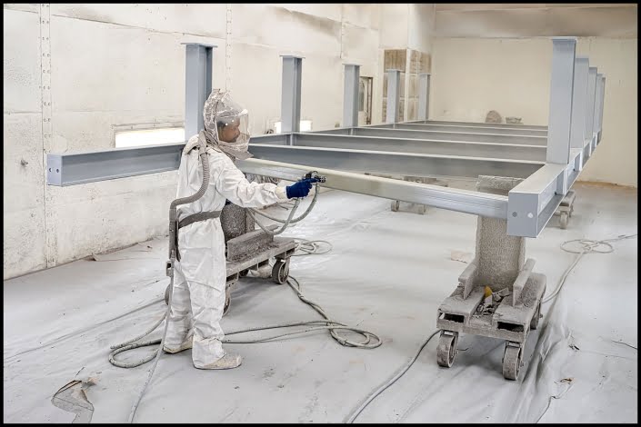 Michael LoBiondo Photography - worker in paint booth spraying large metal girders