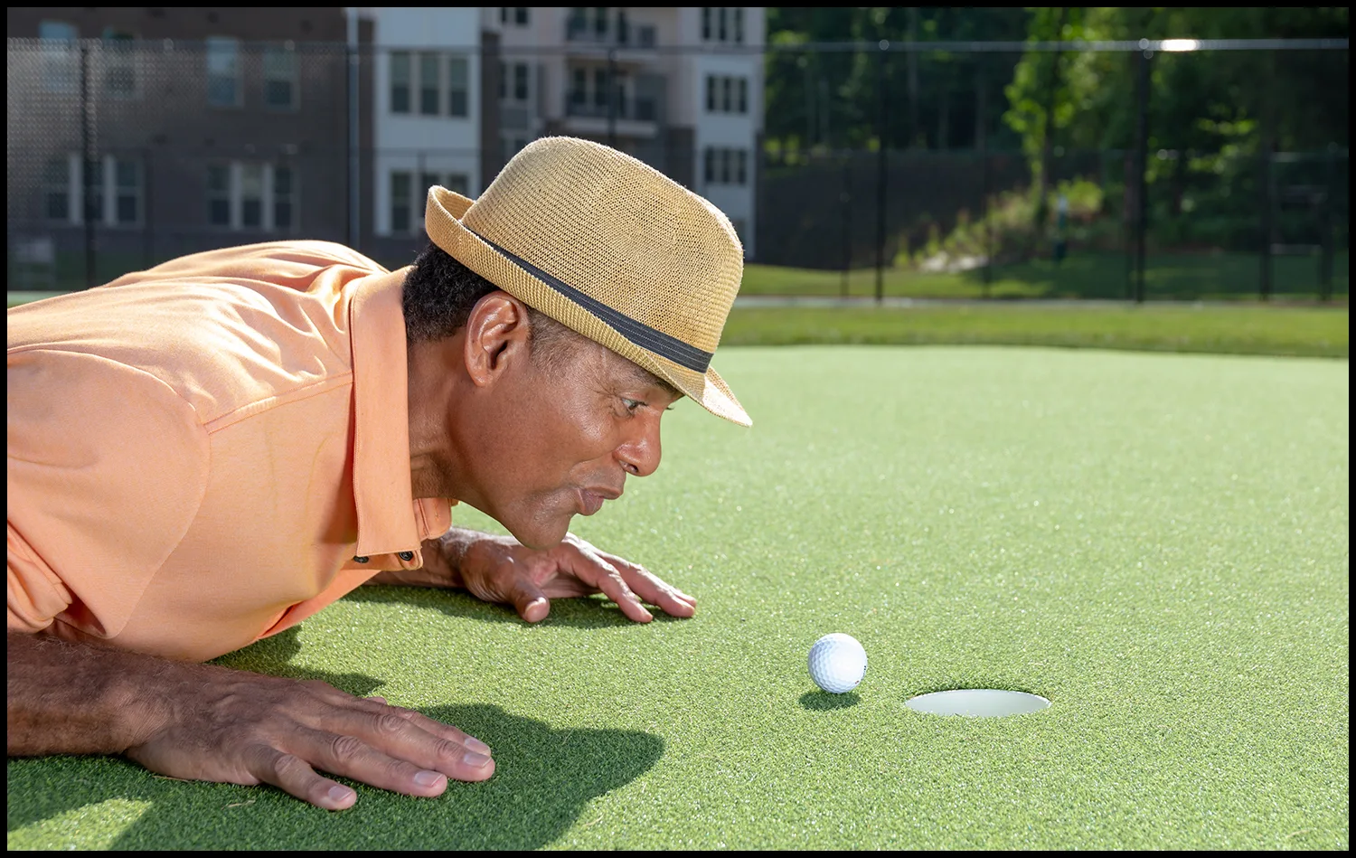 location-golfer-lifestyle-summer-fun Man lining up a putt on a golf green during a lifestyle photoshoot