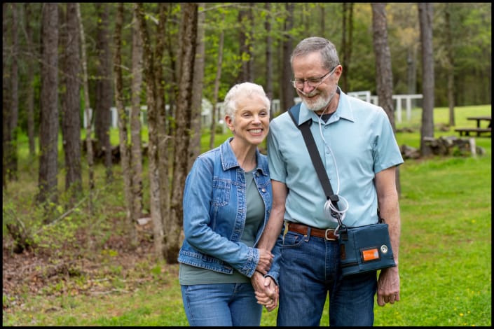 Senior couple walking outdoors with portable oxygen concentrator