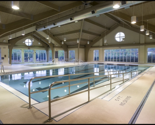Indoor swimming pool with exposed wood beams and large windows