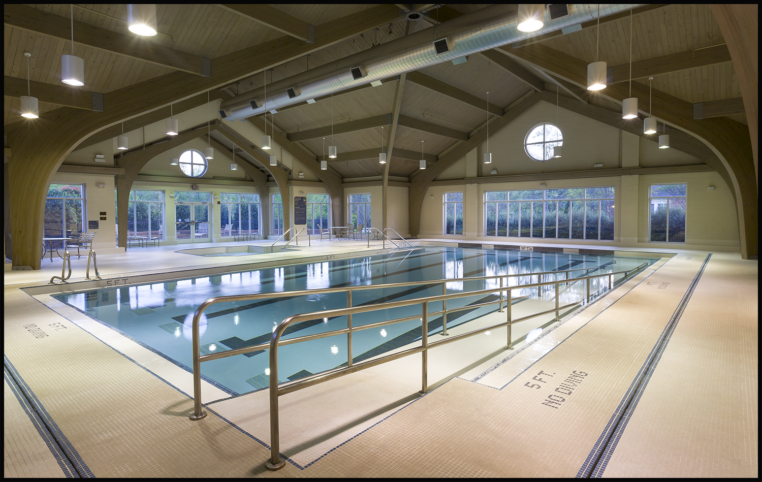 Indoor swimming pool with exposed wood beams and large windows